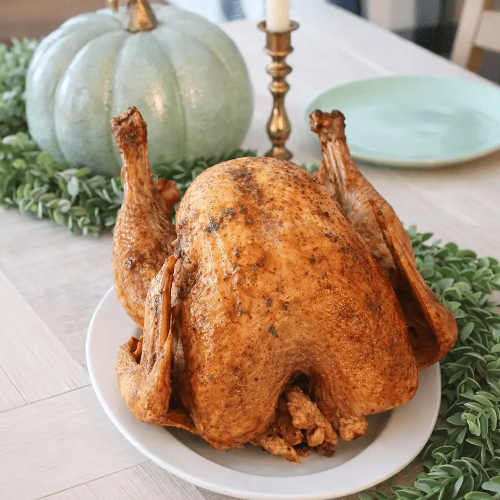 Goldbraun gebratener AirFryer Truthahn auf einem Servierteller mit herbstlicher Tischdekoration