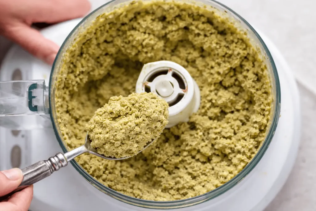 Close-up von frisch gemischtem Falafel-Teig im Foodprocessor, auf einem Löffel gehalten, bereit für den Airfryer