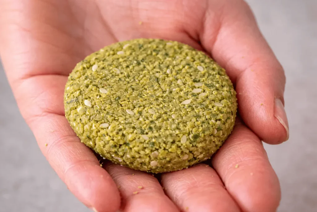 Nahaufnahme einer rohen Falafel-Patties, die in einer Hand gehalten wird, bereit für den Airfryer