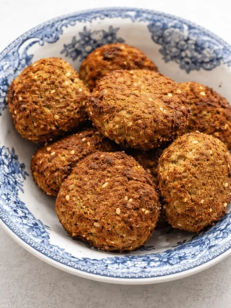 falafel airfryer ​, goldbraun und knusprig, mit Kräutern und Sesam in einem modernen schwarzen Airfryer-Korb