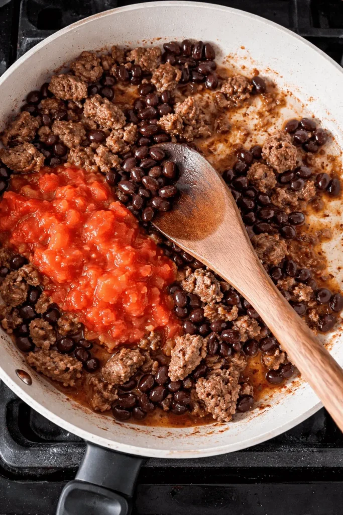 Würzige Hackfleisch-Bohnen-Füllung mit Tomaten und Paprika wird in einer Pfanne für Airfryer gefüllte Paprika gekocht.