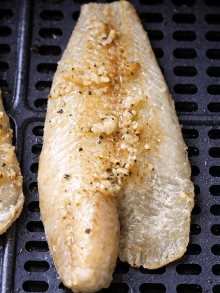 Goldbraun gegartes Seelachsfilet im Korb – Seelachs aus der Heißluftfritteuse mit Knoblauch-Butter.
