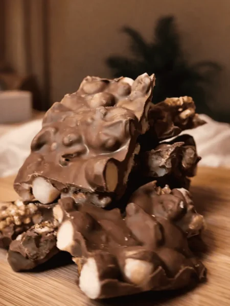 Schokoladige Nussriegel mit ganzen Haselnüssen und Walnüssen auf einem Holzbrett