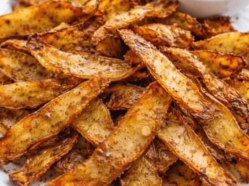 Knusprige Airfryer Kartoffelschalen mit Gewürzen und cremigem Dip auf einem weißen Teller